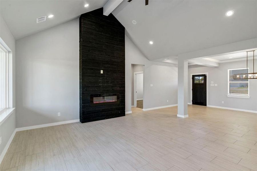 Unfurnished living room with a tile fireplace, light hardwood / wood-style floors, and beam ceiling