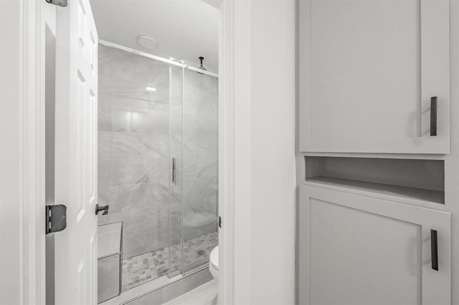 Bathroom featuring a shower with shower door and toilet