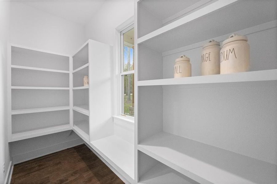 This expansive pantry boasts a generous layout and is illuminated by a charming window, allowing natural light to fill the space. With ample room to store groceries and essential items, it offers a perfect solution for organization and convenience.