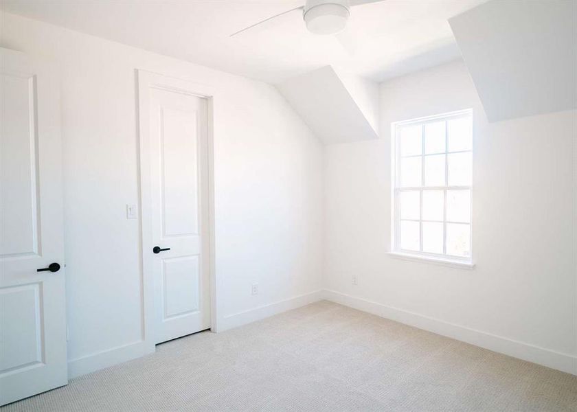 Additional living space with ceiling fan and light colored carpet