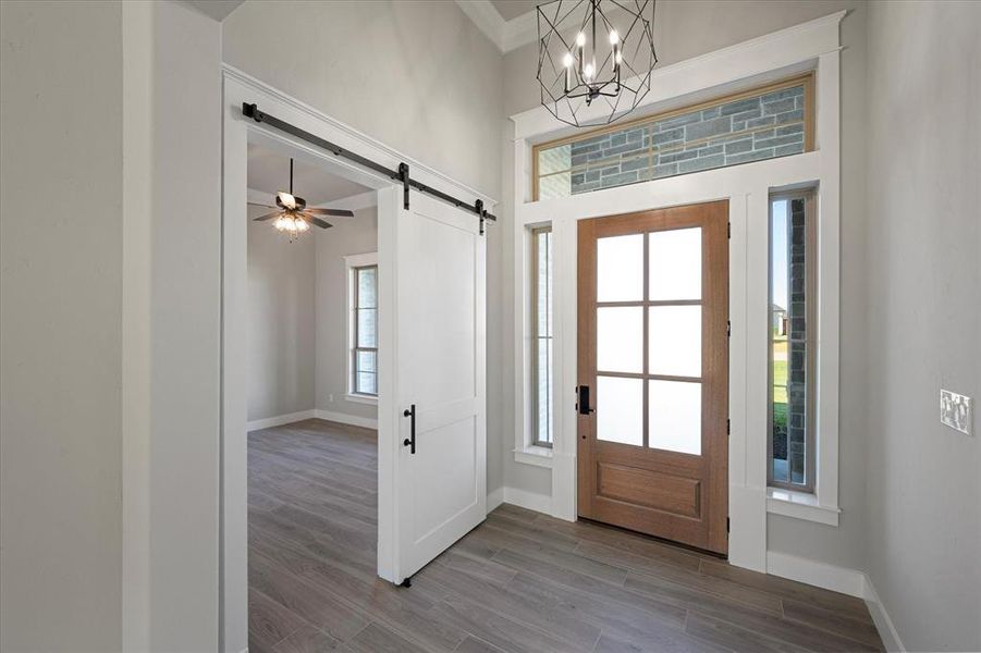 Foyer entrance with ornamental molding, a wealth of natural light, a barn door, and privacy front door