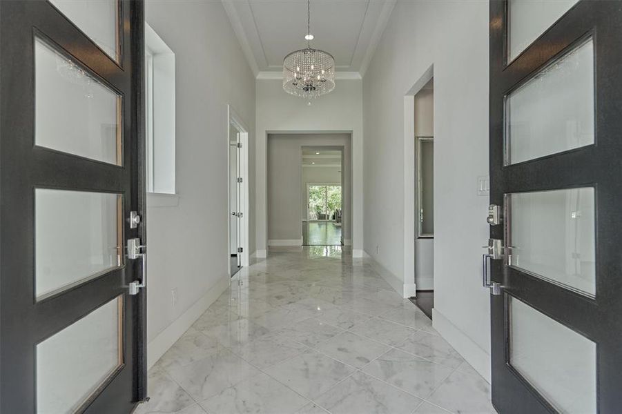 Stunning gallery entry with modern glass panel, double doors, calm white interiors and beautiful marble flooring. Soaring ceilings and crown molding throughout!