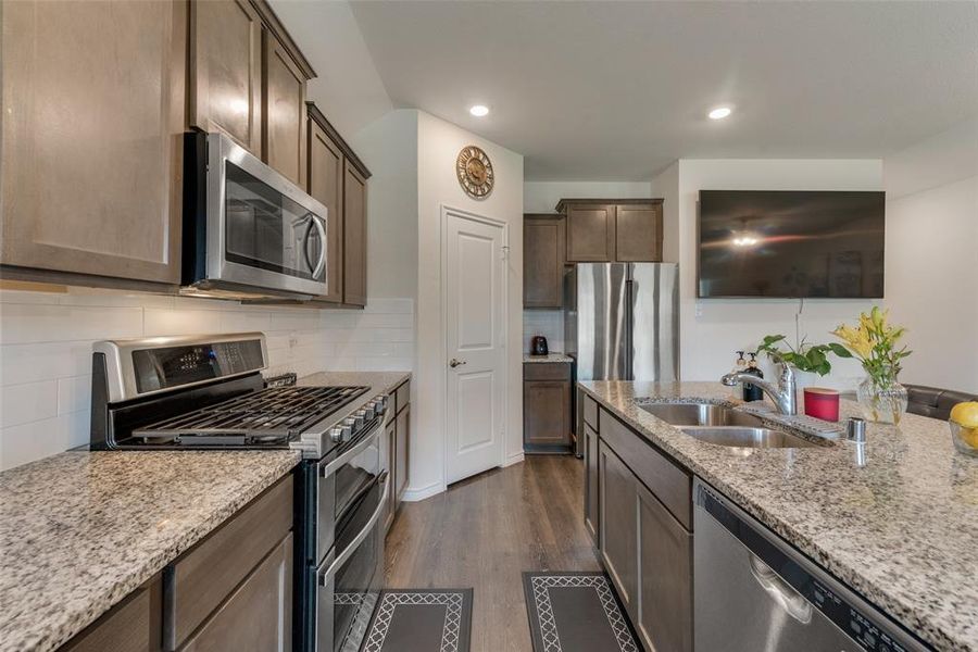 Kitchen with appliances with stainless steel finishes, tasteful backsplash, sink, and dark wood-type flooring