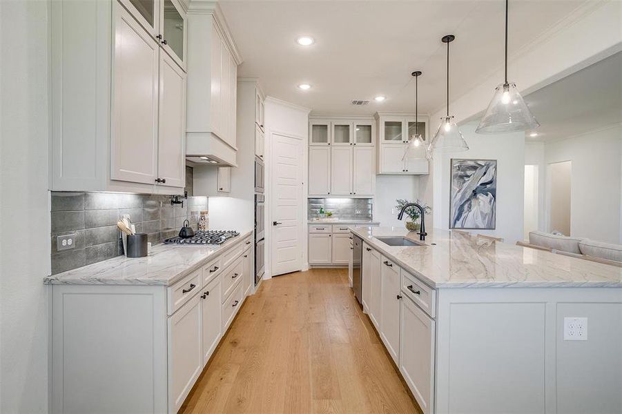 Kitchen with white cabinetry, sink, and an island with sink