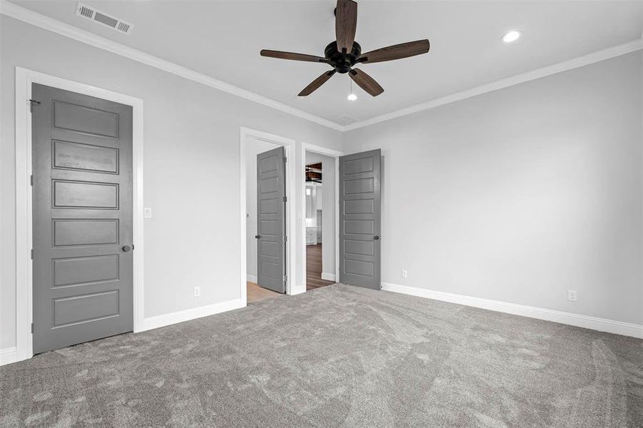 Unfurnished bedroom featuring carpet, ornamental molding, and ceiling fan