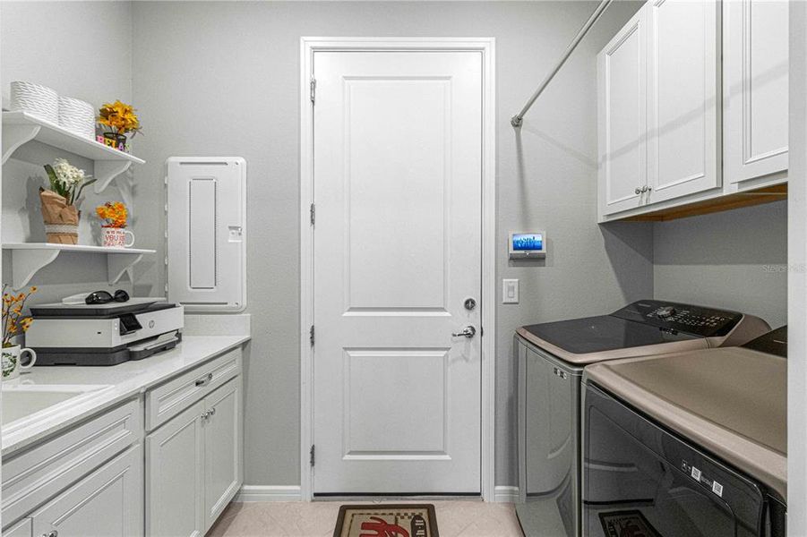 Upgraded laundry, with sink, folding area and cabinetry