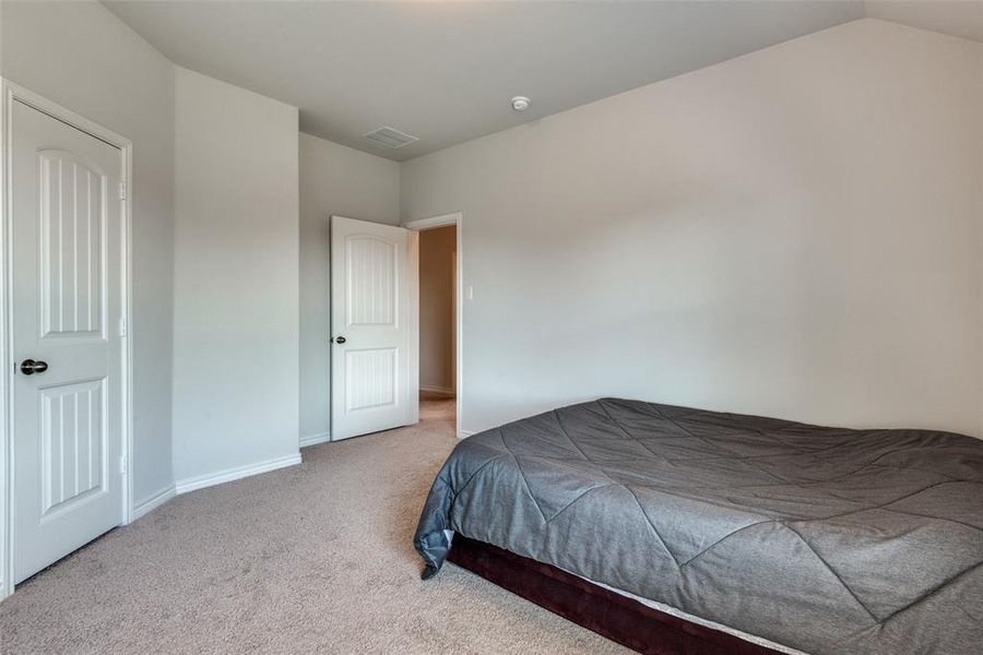 Bedroom featuring light colored carpet and vaulted ceiling