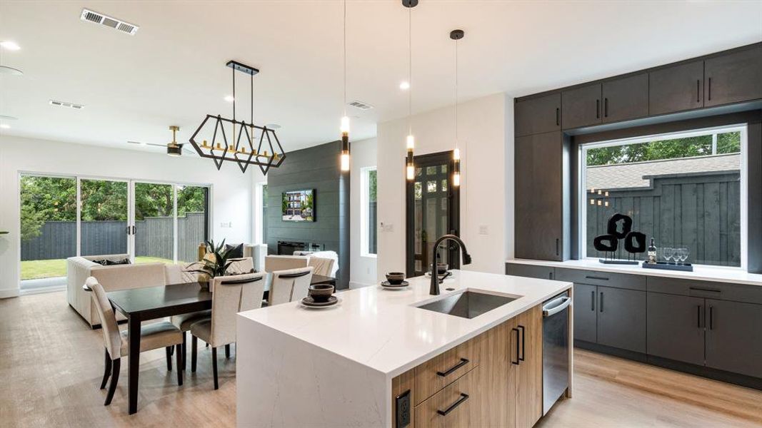 Kitchen with sink, an island with sink, light hardwood / wood-style flooring, and pendant lighting