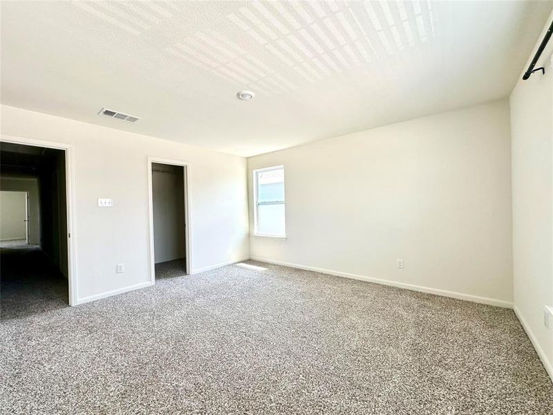 Unfurnished bedroom with a spacious closet and carpet