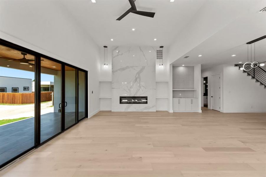 Living room with ceiling fan, light hardwood / wood-style flooring, and a premium fireplace