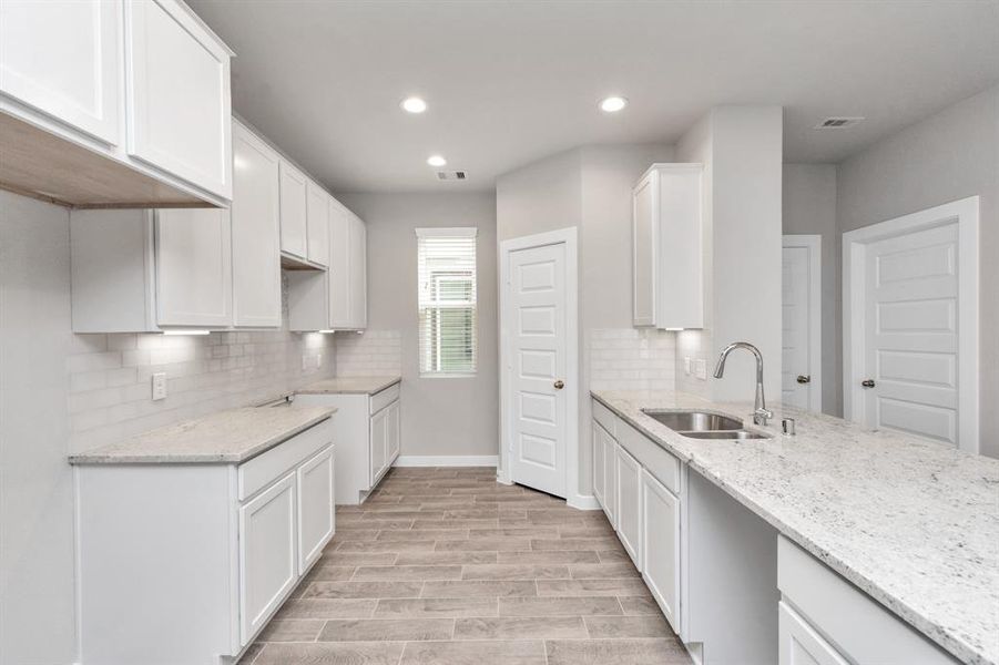 This generously spacious kitchen is a dream realized! With high ceilings, soft close cabinets, granite countertops, stainless steel appliances, a sleek tile backsplash, recessed lighting, and an extended counter area, it offers both style and practicality. All this opens up to the expansive family room, creating a perfect hub for gatherings. Sample photo of completed home with similar floor plan. As-built interior colors and selections may vary.