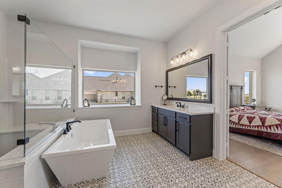 Bathroom featuring vanity, a notable chandelier, a washtub, and a healthy amount of sunlight