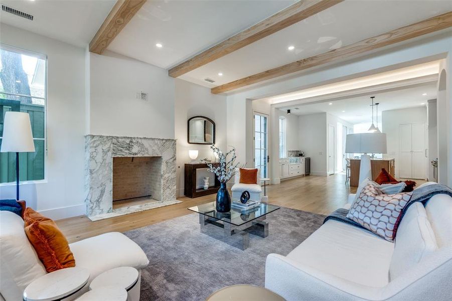 Living room with beamed ceiling, a high end fireplace, and light hardwood / wood-style flooring