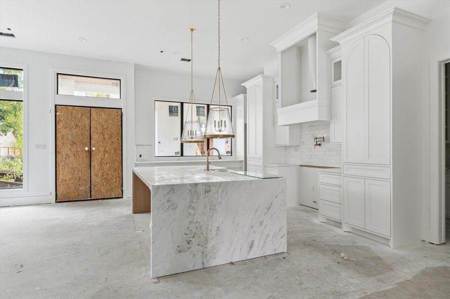 This kitchen is perfection!  Statement island with waterfall Dolomite countertop, accented with designer pendents (soon to be adjusted).  Gorgeous antique bronze hardware to be installed on the site-built cabinetry.  Every detail in this home is exquisite.  Photo as of 9/3/2024