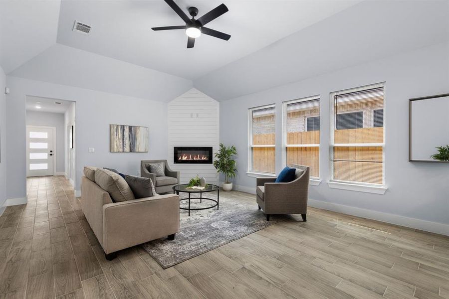 Living room featuring lofted ceiling, a fireplace, ceiling fan, and a wealth of natural light