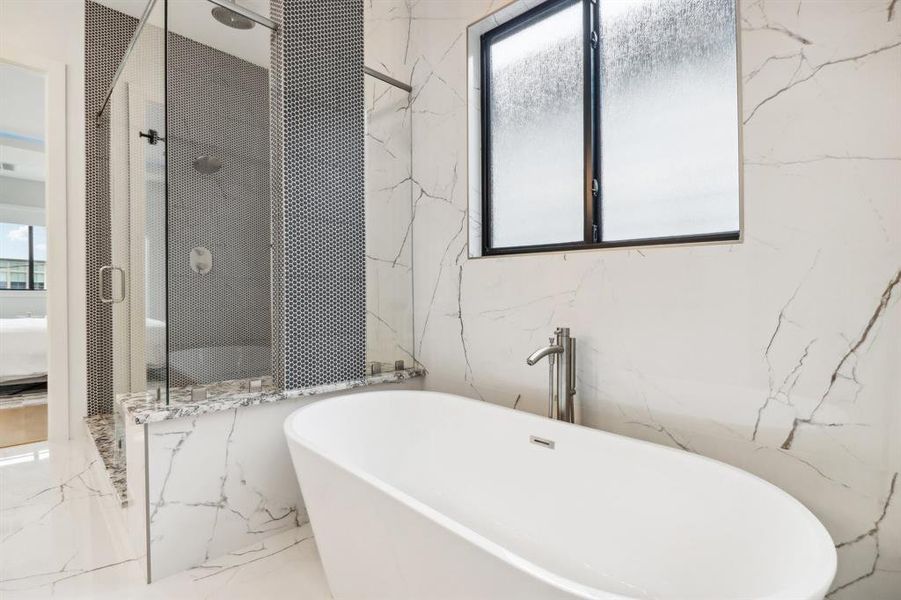 Gorgeous quartz material is used on the flooring and the walls. Freestanding tub is nestled on the other side of the shower.