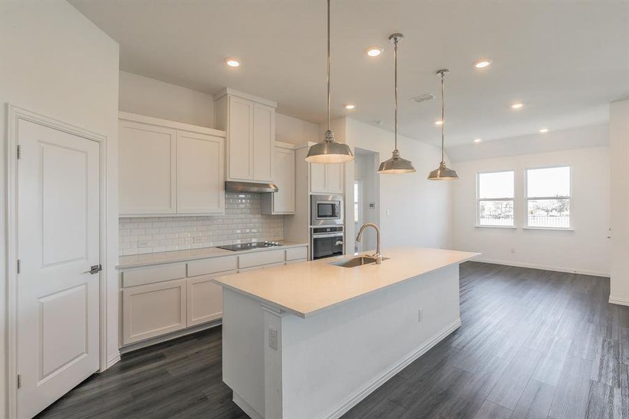 Kitchen featuring pendant lighting, white cabinetry, stainless steel appliances, a center island with sink, and dark hardwood / wood-style flooring