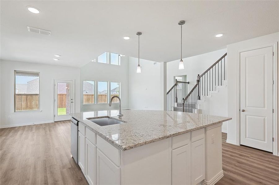 Kitchen featuring sink, white cabinets, hardwood / wood-style flooring, and a kitchen island with sink