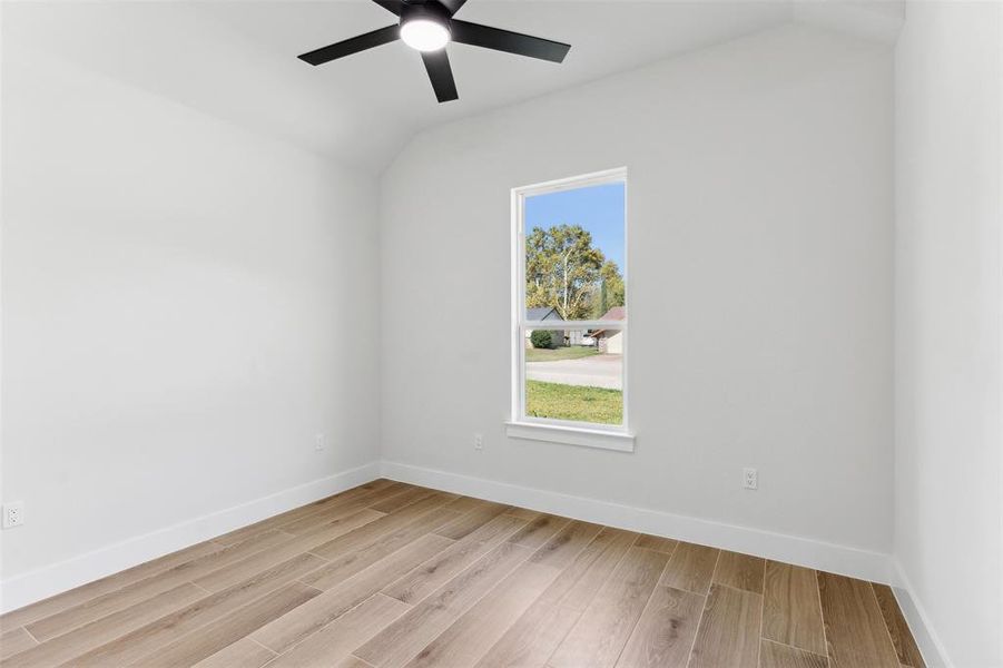 Spare room with ceiling fan, light hardwood / wood-style flooring, and lofted ceiling