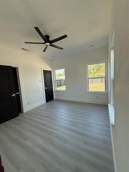 Seconday bedroom featuring light hardwood / Luxury vinyl/wood-style flooring, multiple windows, and ceiling fan