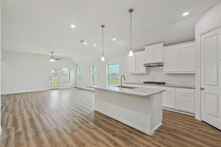 Kitchen with a healthy amount of sunlight, hardwood / wood-style floors, ceiling fan, and tasteful backsplash