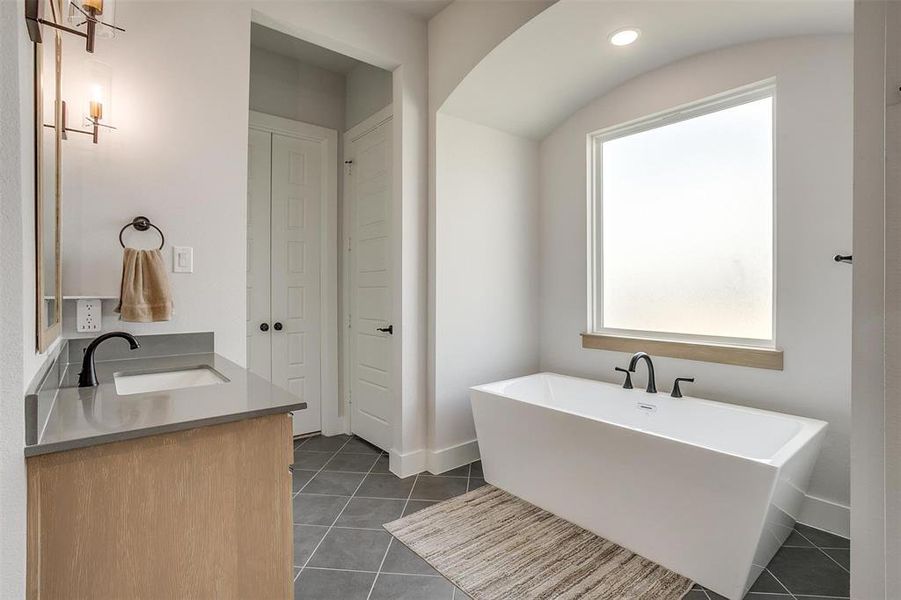 Bathroom featuring vanity, tile patterned floors, and a bathing tub