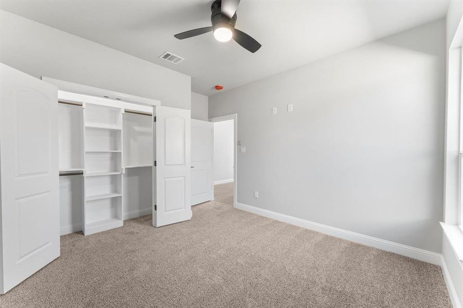 Unfurnished bedroom featuring light carpet, ceiling fan, and a closet