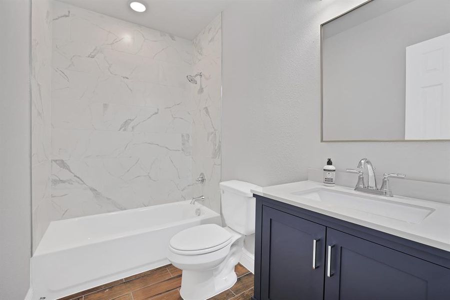 Full bathroom featuring toilet, tiled shower / bath, hardwood / wood-style flooring, and vanity