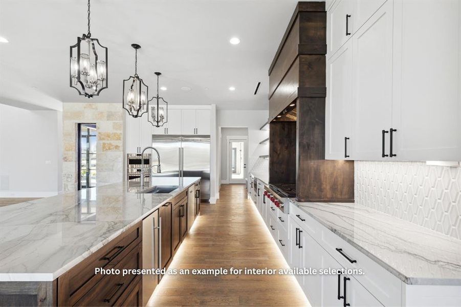 Kitchen featuring light stone countertops, light hardwood / wood-style flooring, white cabinets, and pendant lighting