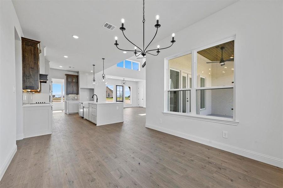 Unfurnished living room featuring hardwood / wood-style flooring and ceiling fan with notable chandelier