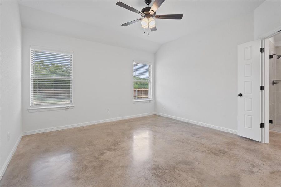 Empty room featuring ceiling fan, vaulted ceiling, and a healthy amount of sunlight