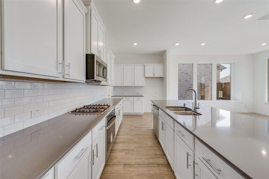 Kitchen with sink, white cabinetry, light hardwood / wood-style flooring, and stainless steel appliances