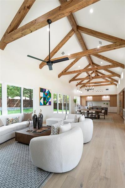 Living room with ceiling fan, beamed ceiling, light wood-type flooring, and high vaulted ceiling