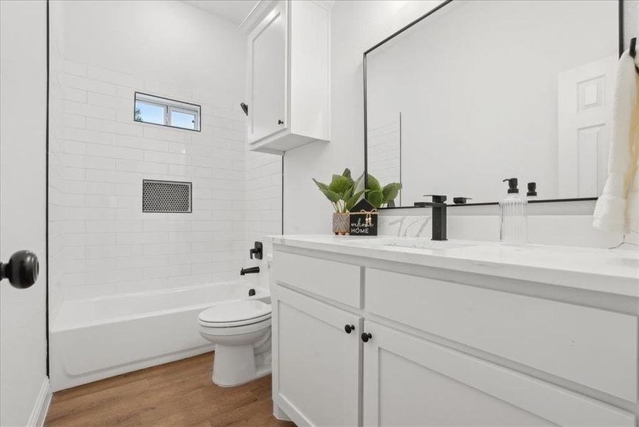 Full bathroom featuring vanity, toilet, tiled shower / bath combo, and wood-type flooring