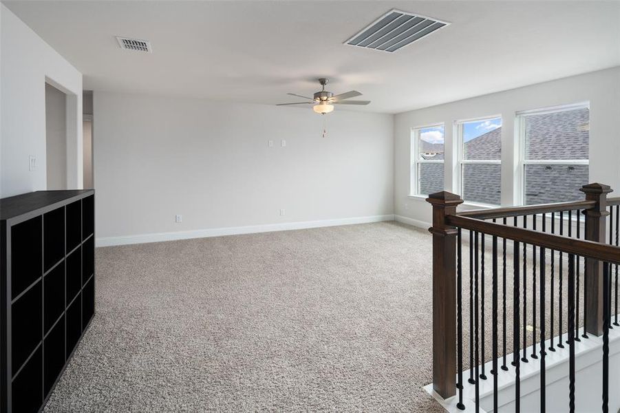 Carpeted spare room featuring ceiling fan