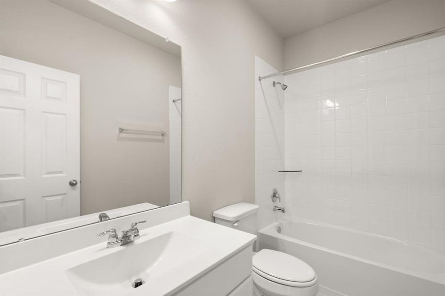 The secondary bath features tile flooring, white cabinetry and light countertops and a shower/tub combo. Perfect for accommodating any visiting family and friends.