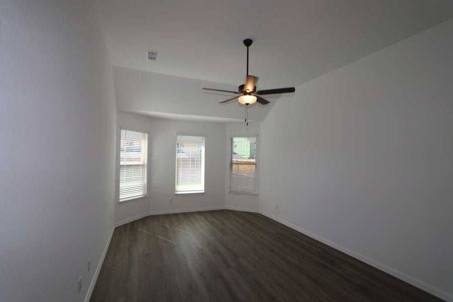 Spare room with dark wood-type flooring and ceiling fan