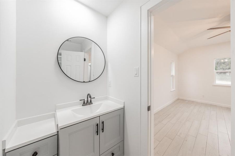 Bathroom featuring ceiling fan, vanity, vaulted ceiling, and hardwood / wood-style flooring