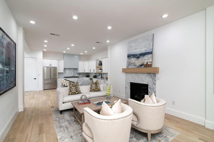 Living room with a premium fireplace, light hardwood / wood-style floors, and sink