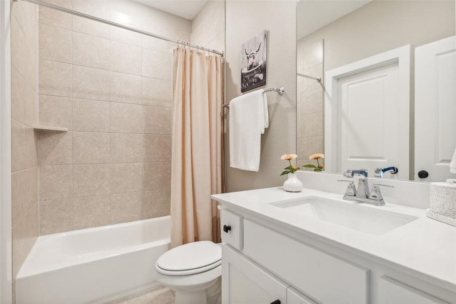 Full bathroom featuring vanity, toilet, and shower / bathtub combination with curtain