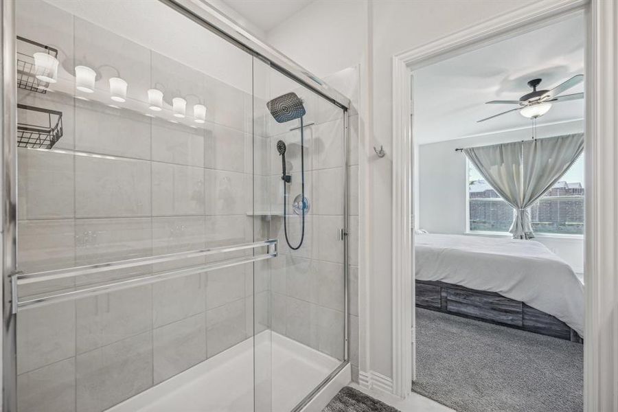 Bathroom featuring ceiling fan and a shower with door