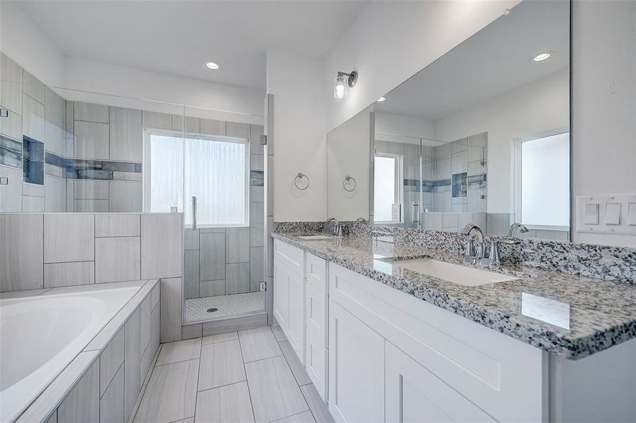 Please visit 6410 Leopold Star Lane to see the builder's standard finishes. The primary bathroom boasts double under-mount sinks, a large soaking tub, and a walk-in shower with a seamless glass enclosure.