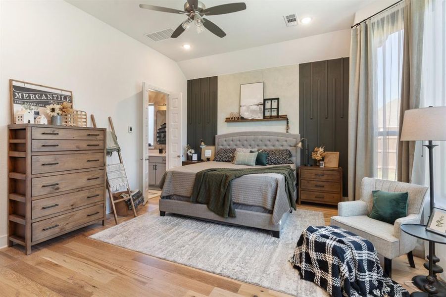 Bedroom with light hardwood / wood-style floors, lofted ceiling, ceiling fan, and ensuite bath