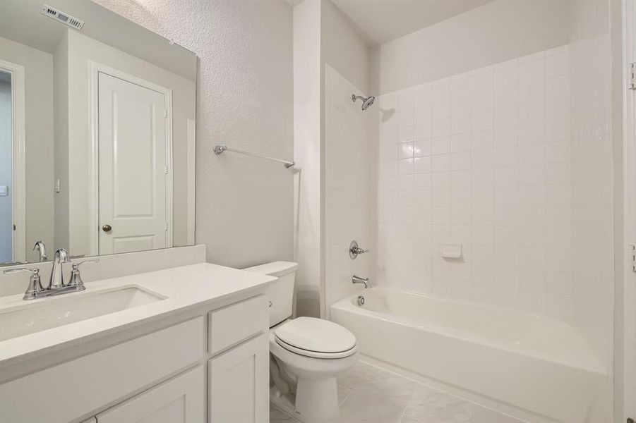 Full bathroom featuring toilet, tiled shower / bath, and vanity