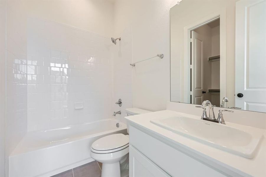 Full bathroom featuring vanity, tiled shower / bath combo, toilet, and tile patterned floors