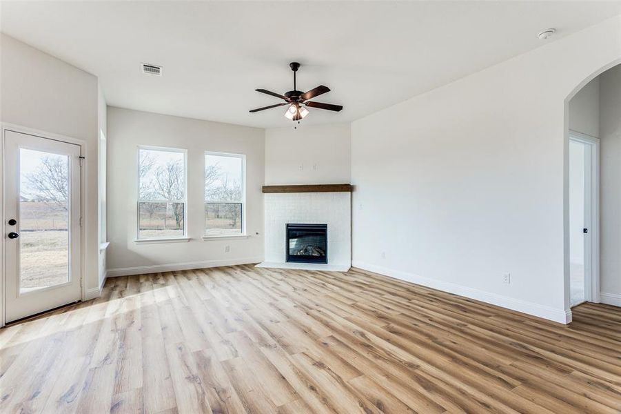 Unfurnished living room with plenty of natural light, ceiling fan, and light wood-type flooring