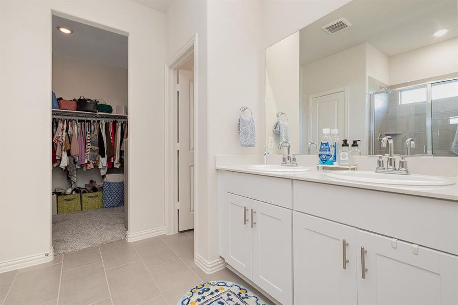 Bathroom featuring walk in shower, vanity, and tile patterned floors