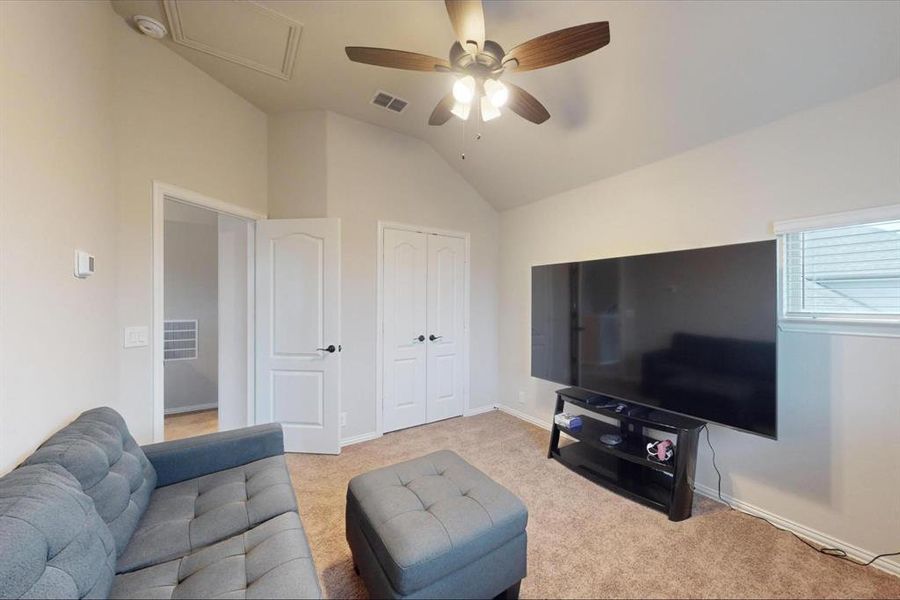 Living room featuring ceiling fan, light carpet, and lofted ceiling