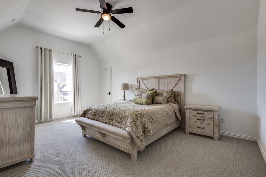 Bedroom with ceiling fan, lofted ceiling, and light colored carpet