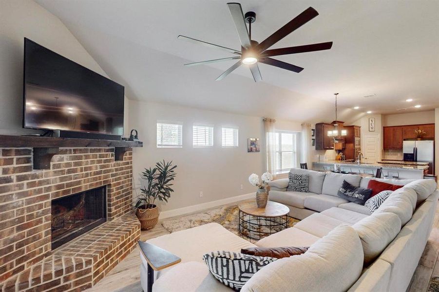 Living room featuring a brick fireplace, sink, ceiling fan, and light hardwood / wood-style floors